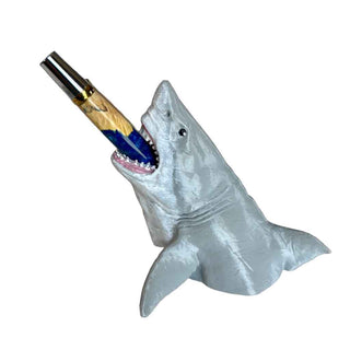 Shark-shaped pen holder with a pen inside on a white background