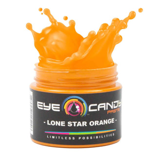 Jar of 'Lone Star Orange' eye candy paste with splashing orange substance on a white background