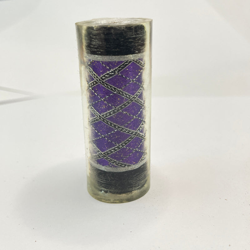 Cylindrical pen blank with purple interior and black exterior on a white background