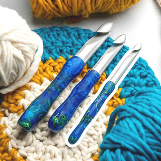 Set of three crochet hooks with blue handles on a knitted fabric background