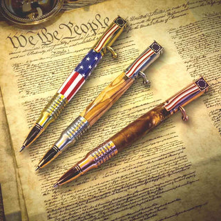 Three American flag-themed pens on a document with 'We the People' printed on it.